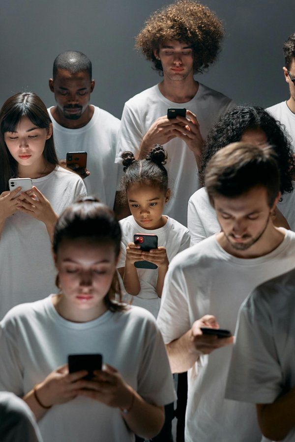 A group of people of various ages and ethnicities, all absorbed in their smartphones, reflecting the impact of technology on mental health.